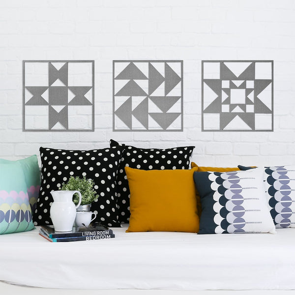 Three metal quilt block design squares hanging on wall above couch. 