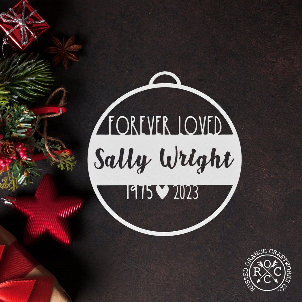 memorial ornament laying flat with christmas decorations nearby