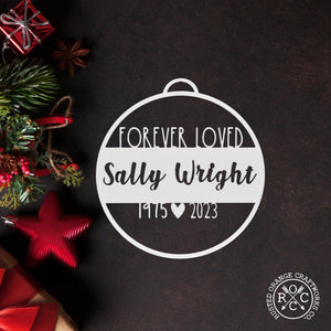 memorial ornament laying flat with christmas decorations nearby