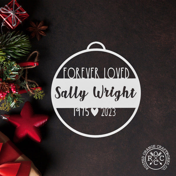 memorial ornament laying flat with christmas decorations nearby