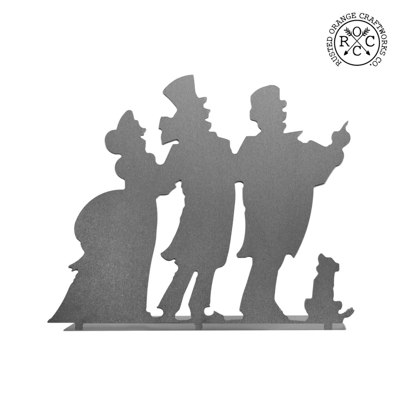 Metal silhouette of 3 Christmas carolers shown against white background.