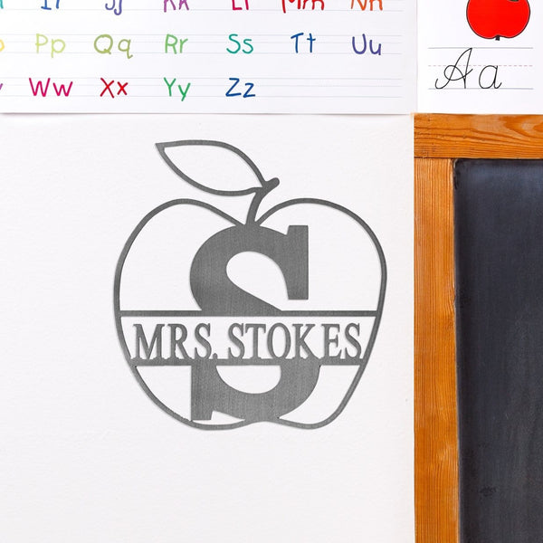 Apple shaped sign with name and monogram in the middle, hanging on classroom wall.