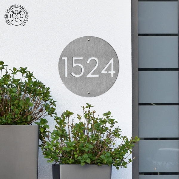 address plaque on wall above house plants