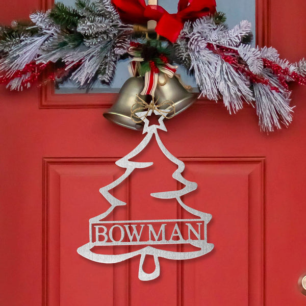 Metal Christmas tree outline with name in center hanging on front door.