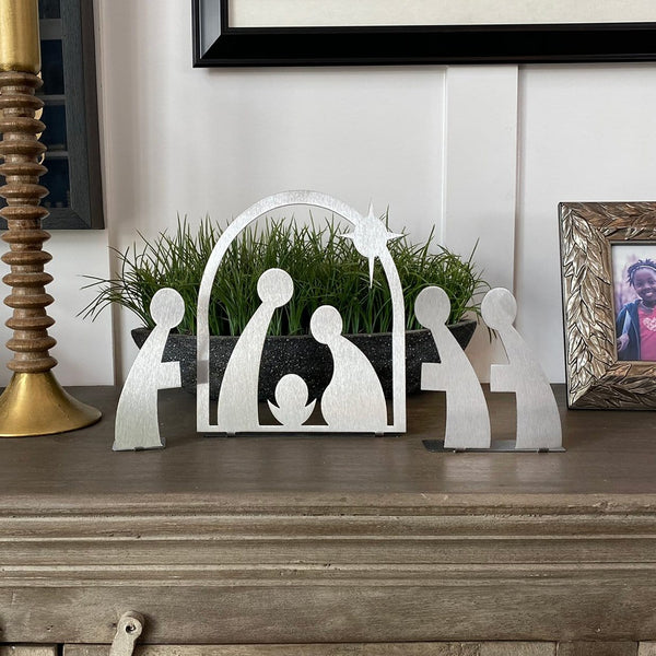 3 piece metal African nativity silhouettes standing on mantel with other home decor.