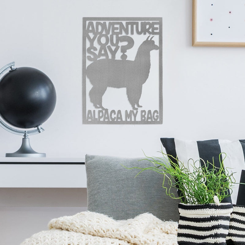 Rectange metal sign with alpaca in center and saying, adventure you say? Alpaca my bag. Hanging on wall above shelf with globe on it.