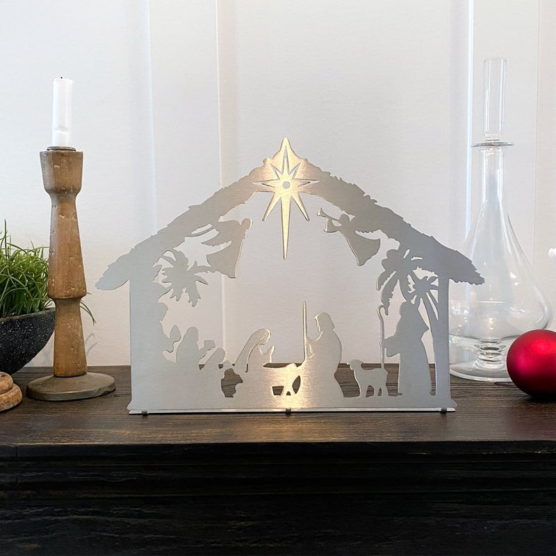 Metal nativity scene silhouette standing on shelf with other decor.