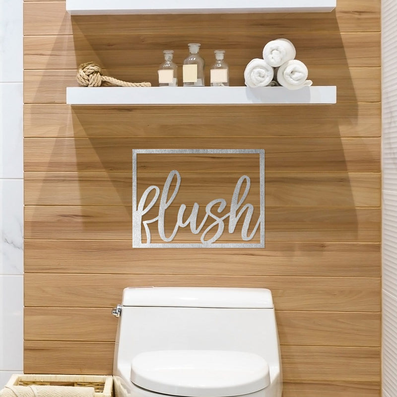 Metal rectangle humorous bathroom phrase sign hanging on wall above toilet.