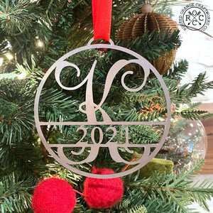 Circle metal ornament with monogram and year 2021, hanging on Christmas tree.