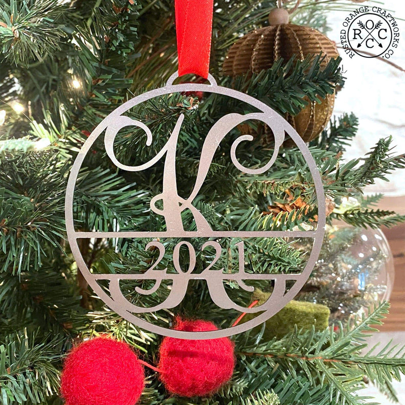 Circle metal ornament with monogram and year 2021, hanging on Christmas tree.