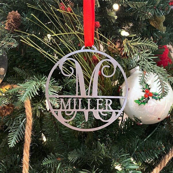 Circle metal ornament with name and monogram hanging on Christmas tree.