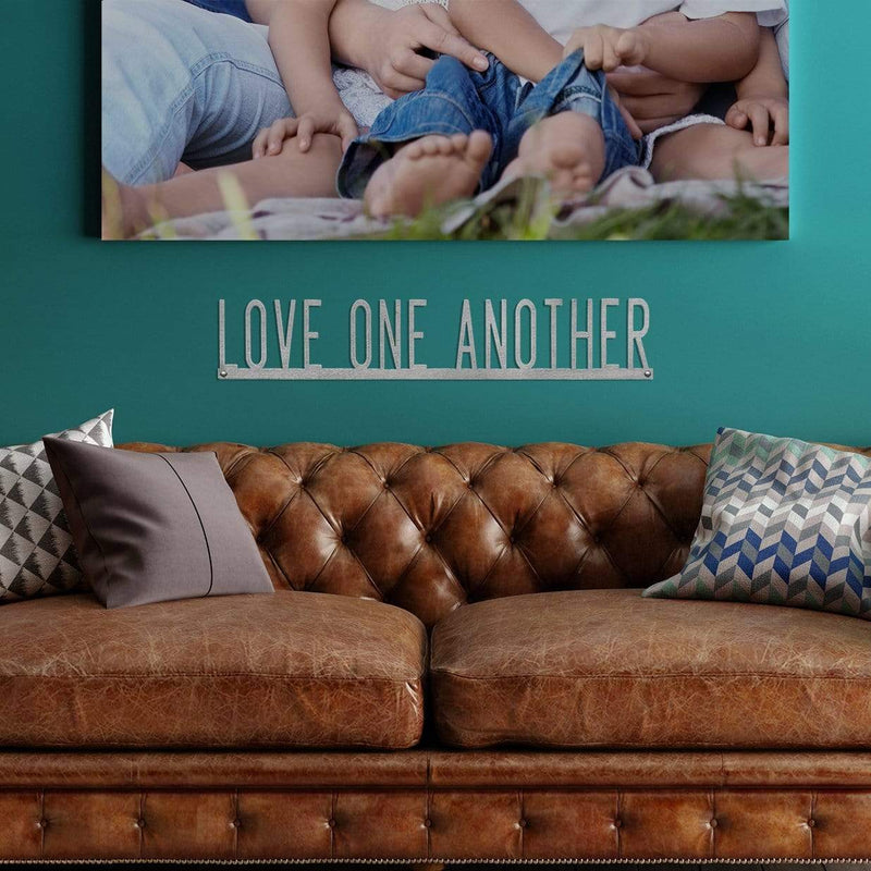 love one another phrase sign on wall above couch