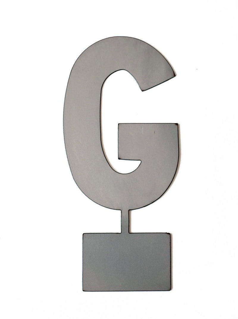 Metal letter G with tab on bottom for standing, shown against white background.