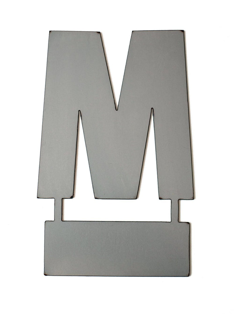 Metal letter M with tab on bottom for standing, shown against white background.