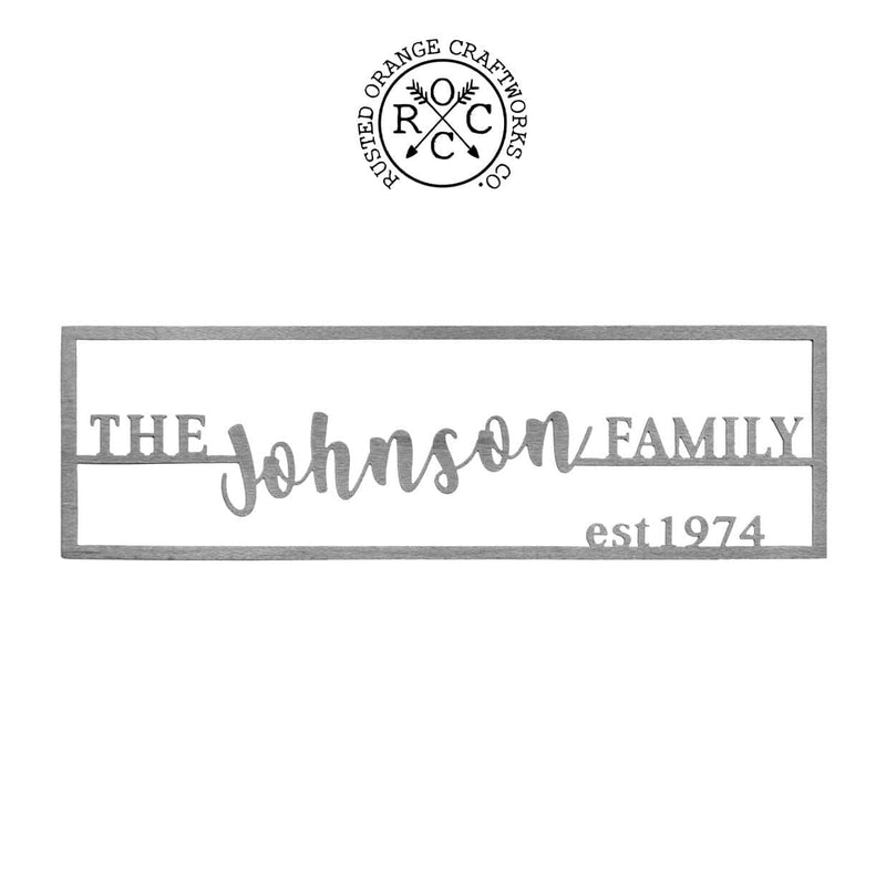 Personalized metal family name and established sign hanging against white background.
