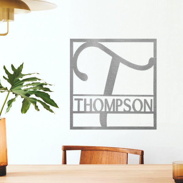 Metal square sign with name and monogram in center, hanging on wall above table.