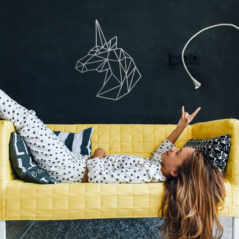 Geometric unicorn sign on wall above girl on couch