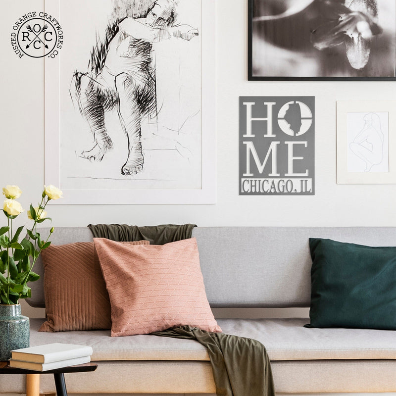 Metal sign saying home with home state silhouette in the oh and city name underneath, hanging on wall above couch.