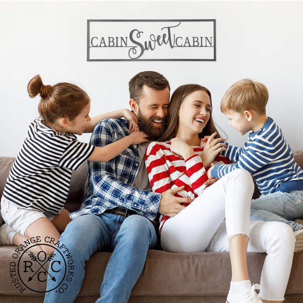 cabin sweet cabin sign above family on couch