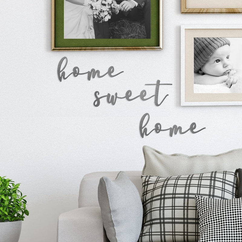 Metal sign saying home sweet home hanging on wall above couch.