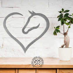 Metal heart shaped horse silhouette hanging on wall above shelf. 