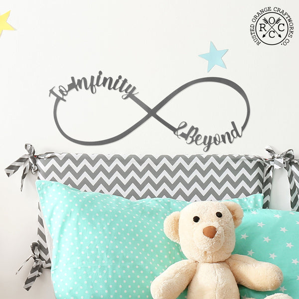 picture of metal infinity sign with To Infinity & Beyond on it hanging over child's bed with teddy bear on bed