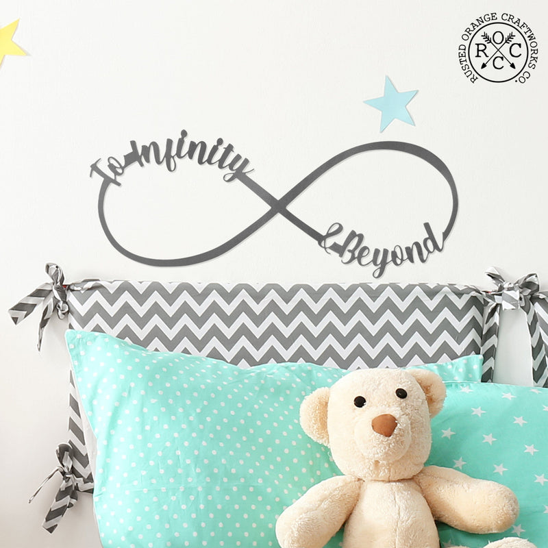 picture of metal infinity sign with To Infinity & Beyond on it hanging over child's bed with teddy bear on bed
