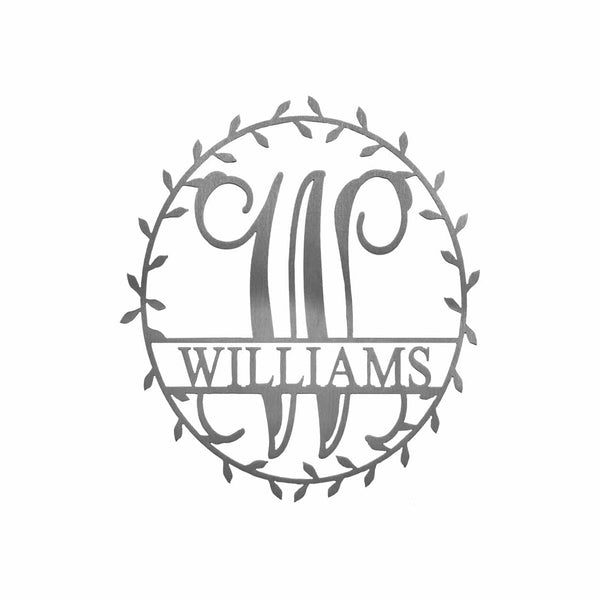 Metal circle sign with name and monogram in center and laurel leaves along edge, against white background.