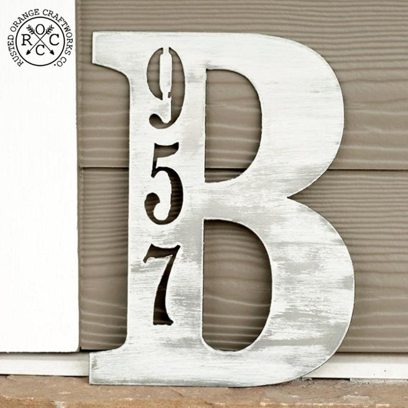 Metal letter with house number inscribed, leaning against house.