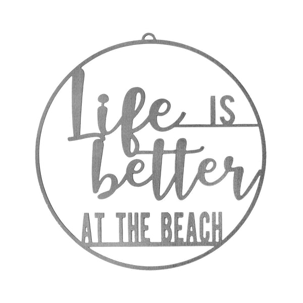 Round metal sign saying life is better at the beach, shown against white background.