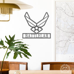 Metal US Air Force symbol with Battlelab etched below it, hanging on wall above table.