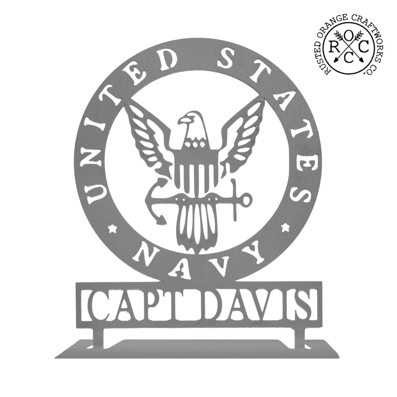 Round metal sign saying United States Navy around the edge and Navy symbol in the center with Capt Davis etched below, shown against white background.