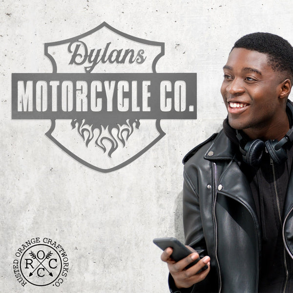 Man with headphones next to hanging metal motorcycle sign which says Dylans Motorcycle Co.
