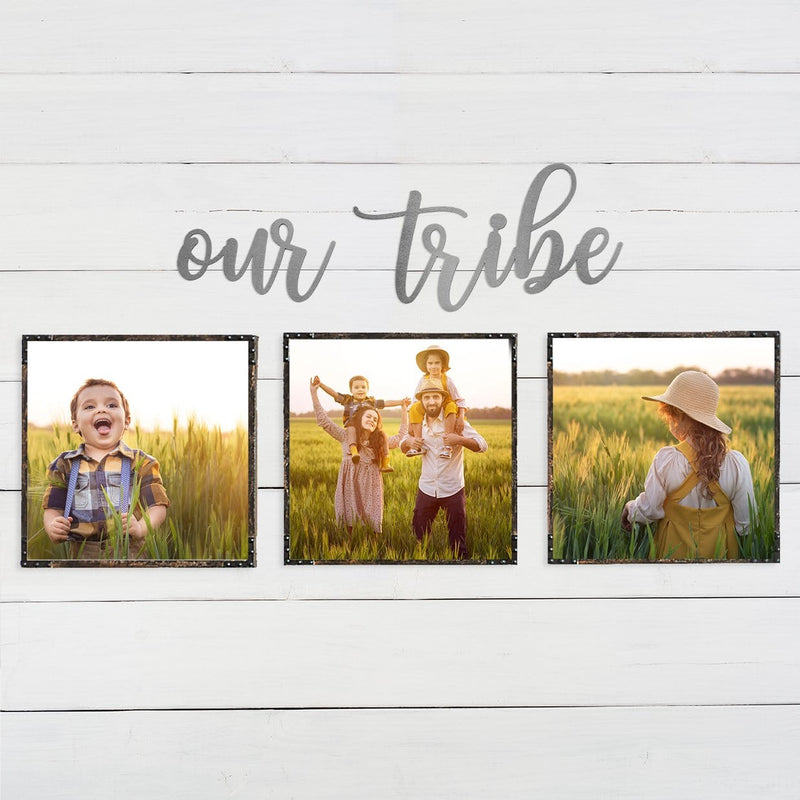 Metal sign saying our tribe hanging on wall above family photos.