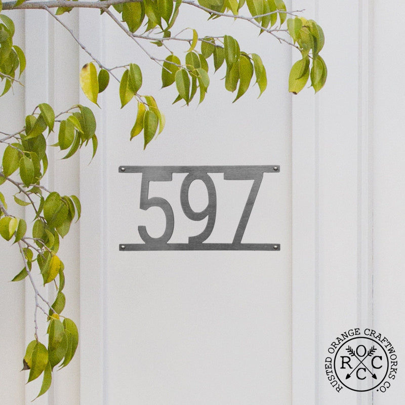 White home exterior with hanging custom metal address number.