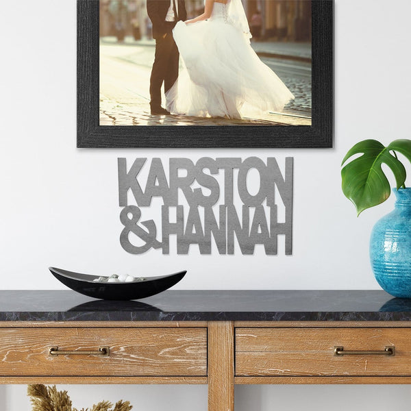 Metal sign of names Karston & Hannah hanging on wall underneath photo of bride and groom.