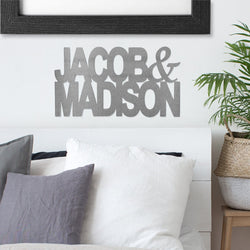 Metal sign of names Jacob & Madison hanging on wall above couch.