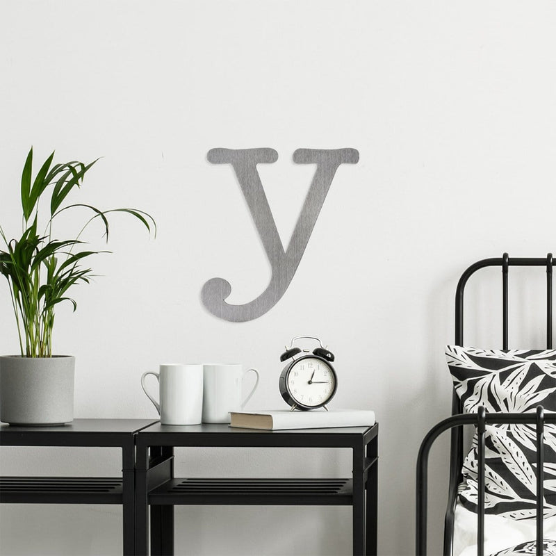 Letter Y metal decoration hanging on wall above bed and nightstand.