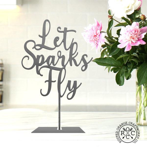 lets sparks fly sign on table by flowers