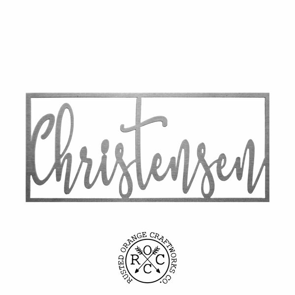 Metal cursive family name sign within rectangle against white background.