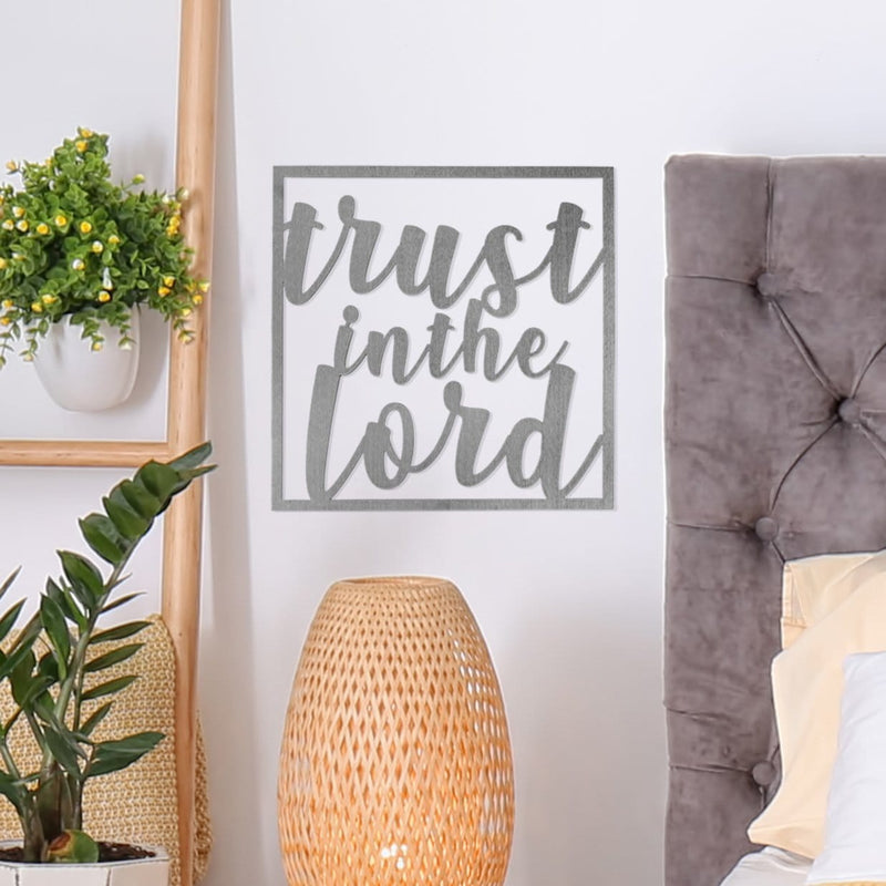 Square metal sign saying trust in the Lord hanging on wall in bedroom.