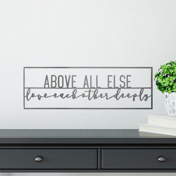 Metal rectangle sign saying above all else love each other deeply, hanging on wall above dresser