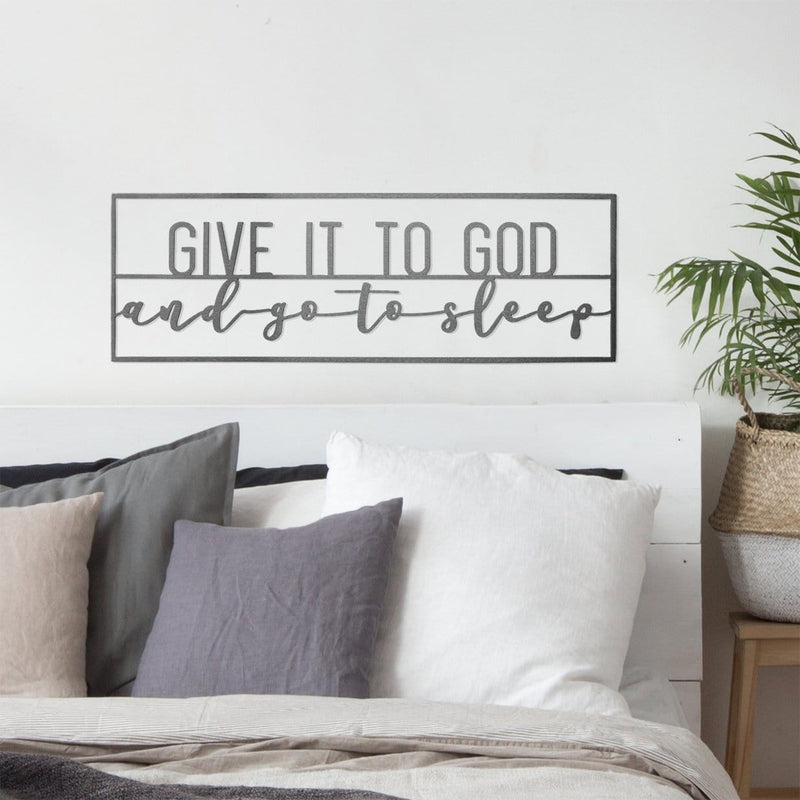 Metal rectangle sign saying give it to god and go to sleep, hanging on wall above bed.